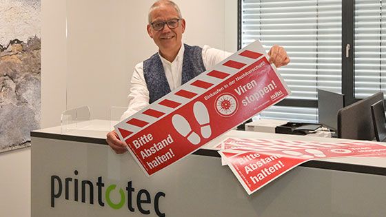 Thomas Beyer von der Spezialdruckerei print-o-tec zeigt die Bodenaufkleber zum Abstandhalten und den Spuckschutz. | Foto: ein