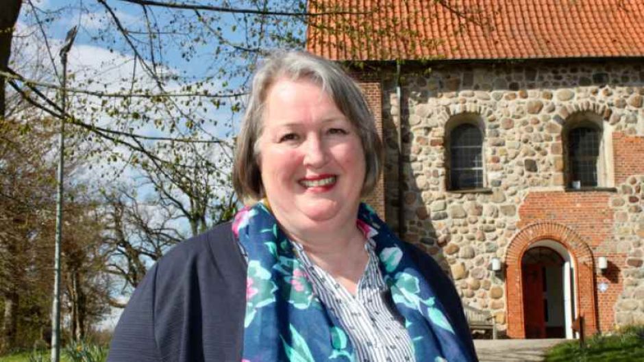 Pastorin Martina Wüstefeld vor der Hittfelder Mauritiuskirche. | Foto: ein