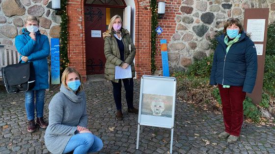 •	Die Krimi-Autorinnen: Britta Oldsen (von links), Pastorin Christina Wolf (kniend), Constanze Cosmann und Gisela Helms mit dem Plakat des Adventskalenders vor der Hittfelder Mauritiuskirche. Pastorin Martina Wüstefeld fehlt auf dem Foto.  | Foto: C. Wöhling