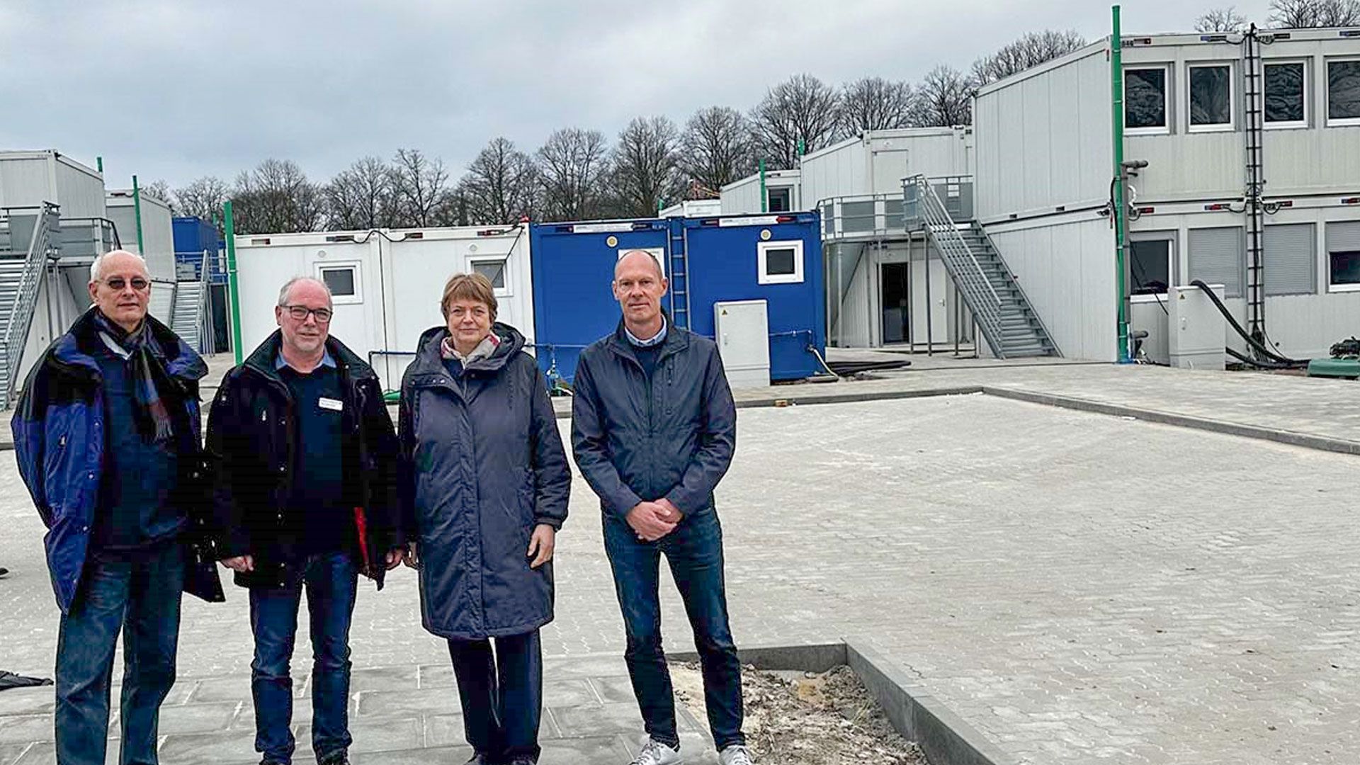 Dr. Andreas B. Kummer (v. l.), Ulrich Bachmeier und Torsten Schult, alle vom DRK-Kreisverband Hamburg-Harburg e. V., mit Staatsrätin Petra Lotzkat vor der Wohnanlage für Geflüchtete auf dem Schwarzenbergplatz. |  Foto: DRK Harburg