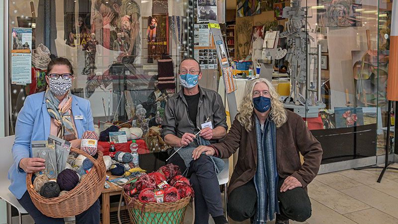 Melanie Wittka, Centermanagerin der Harburg Arcaden, freut sich zusammen mit den Initiatoren von „Harburg Strickt“, dem Künstler Sly (rechts) vom Habibi Atelier im Center und Ulf Möller vom Sozialkontor über die Aktion. | Foto: Niels Kreller