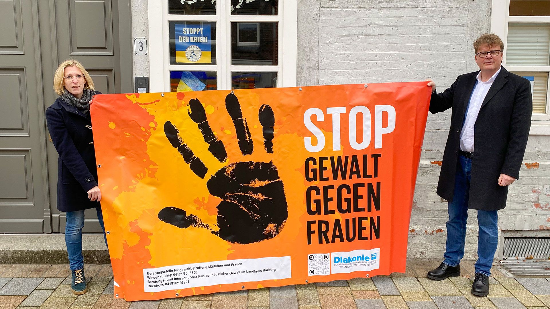 Christine Arndt und Superintendent Christian Berndt weisen mit Bannern auf das Problem der Gewalt gegen Frauen hin. | Foto: Malte Frackmann