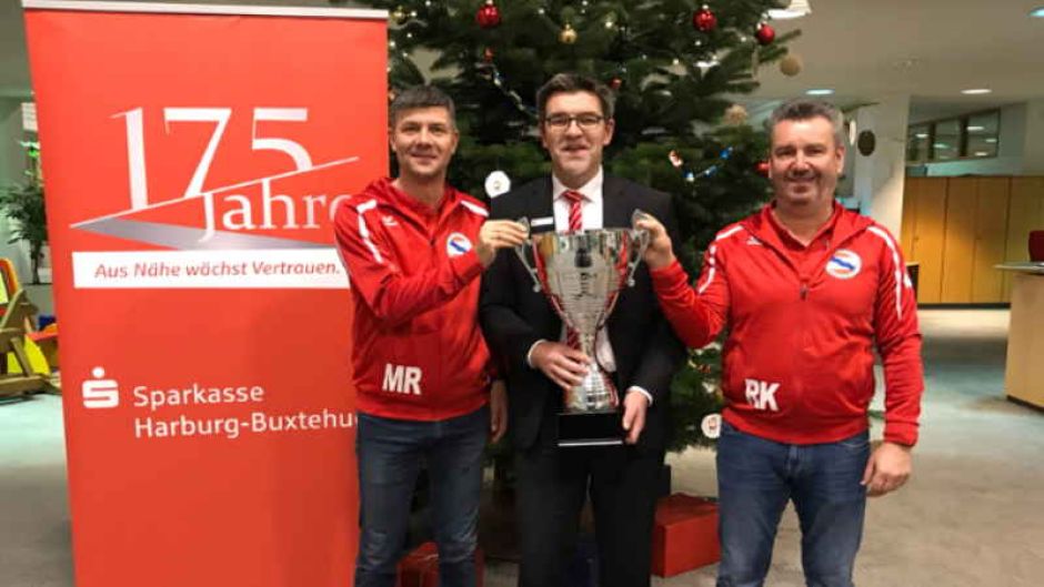 Michael Rump (links) und René Klawon (rechts) vom TSV Eintracht Immenbeck freuen sich gemeinsam mit Stefan Behnke vom Titelsponsor Sparkasse Harburg-Buxtehude auf spannende Spiele beim Sparkassen-Cup 2019. | Foto: ein