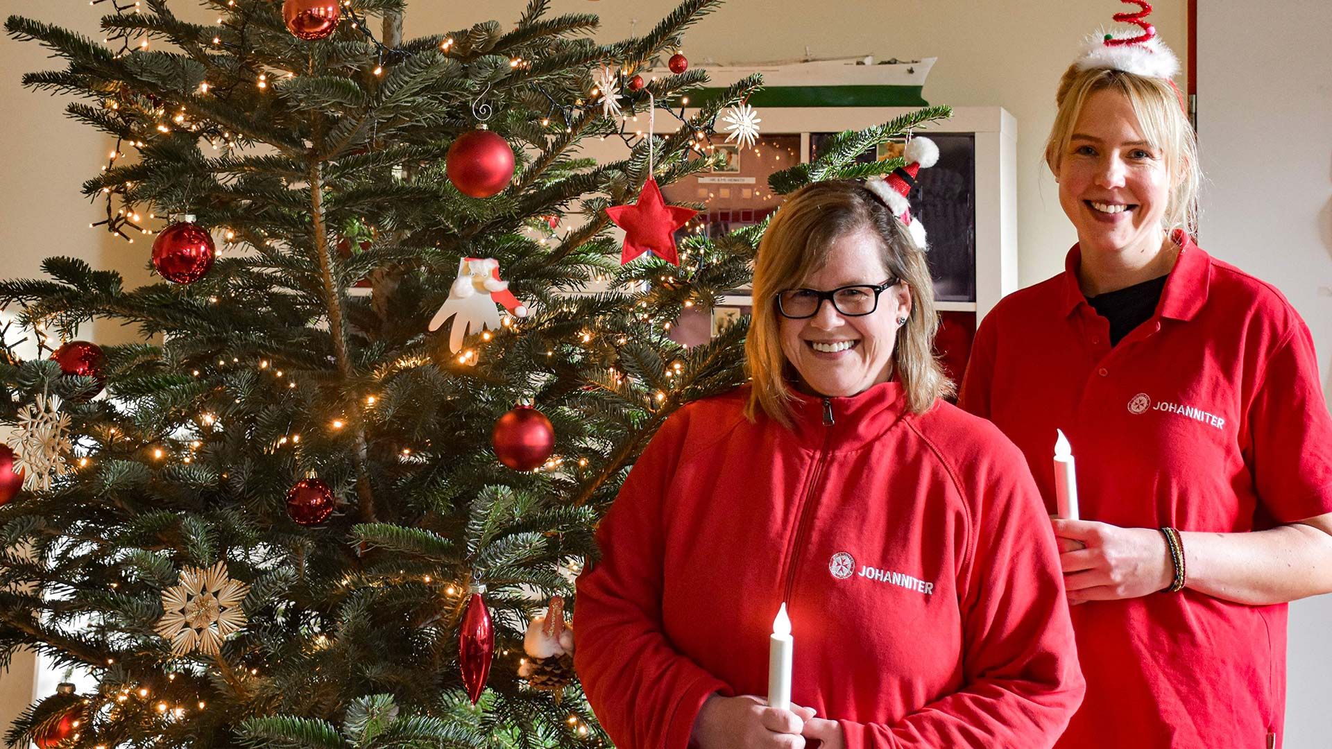 Feiern mit den Tagesgästen an Heiligabend im festlich geschmückten „Wohnzimmer“ der Johanniter-Tagespflege Marmstorf: Sonja Eikhof (links) und Teammitglied Sarah Manoudis. Foto: Johanniter