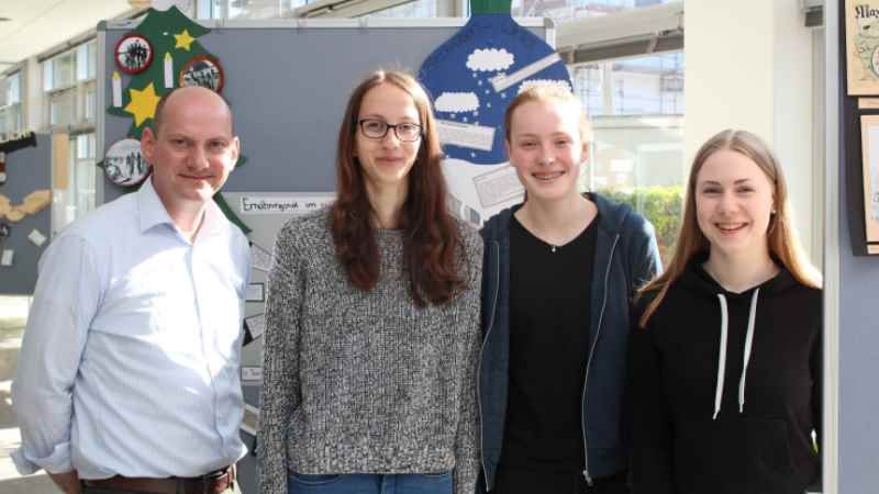 Zehntklässler der Johann-Peter-Eckermann Realschule präsentieren ihre Ausstellung zum Thema Amerikanisierung Europas. Gemeinsam mit ihrem Geschichtslehrer und stellvertretendem Schulleiter Andreas Neises bauten Pia Sommerschmied, Ellen Lorenzen und Fabienne Timm die Ausstellung im Kreishaus in Winsen auf. | Foto: ein