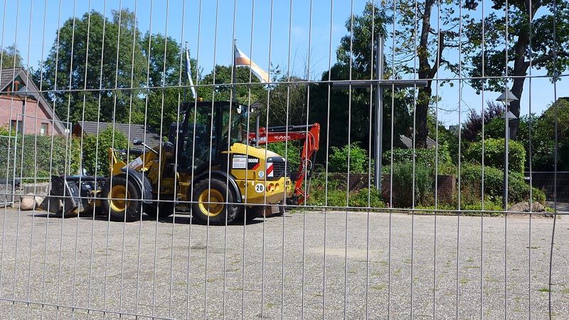 Die Fischbeker Cornelius-Kirche ist seit kurzem von einem Bauzaun umstellt. Die Kirche im Käfig und vor dem Kreuz stehen Bagger. Die Erneuerung der Außenanlagen hat begonnen. | Foto: ein