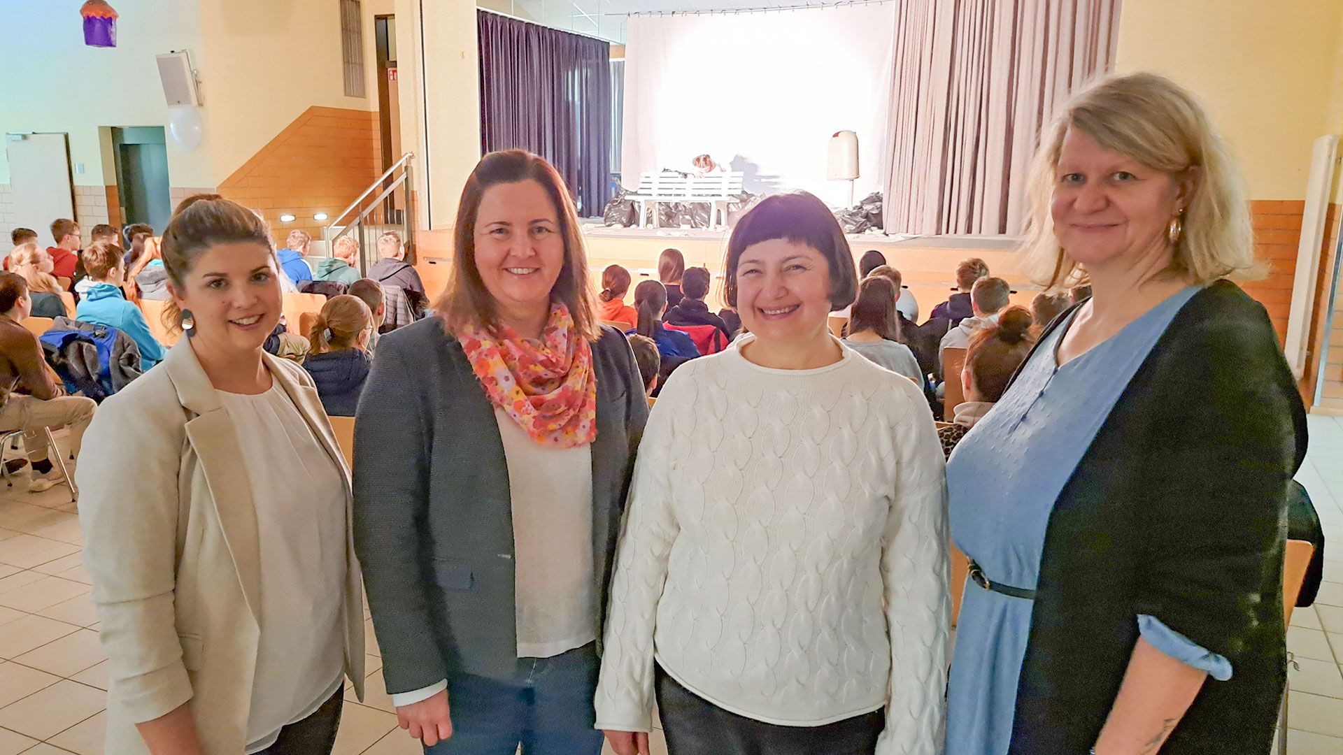 Carina Roder (von links, kommissarische Konrektorin OBS), Marina Otto (Schulsozialpädagogin der OGS und IGS) und Andrea Jahns (kommissarische Schulleiterin der IGS) danken Kristina Rathke (stellvertretende Regionalleiterin der Sparkasse Harburg-Buxtehude, 2. V. l.) für die Unterstützung. Im Hintergrund läuft das Theaterstück „Koma“ für die Siebtklässler zum Thema Alkoholabhängigkeit. | Foto: Sparkasse