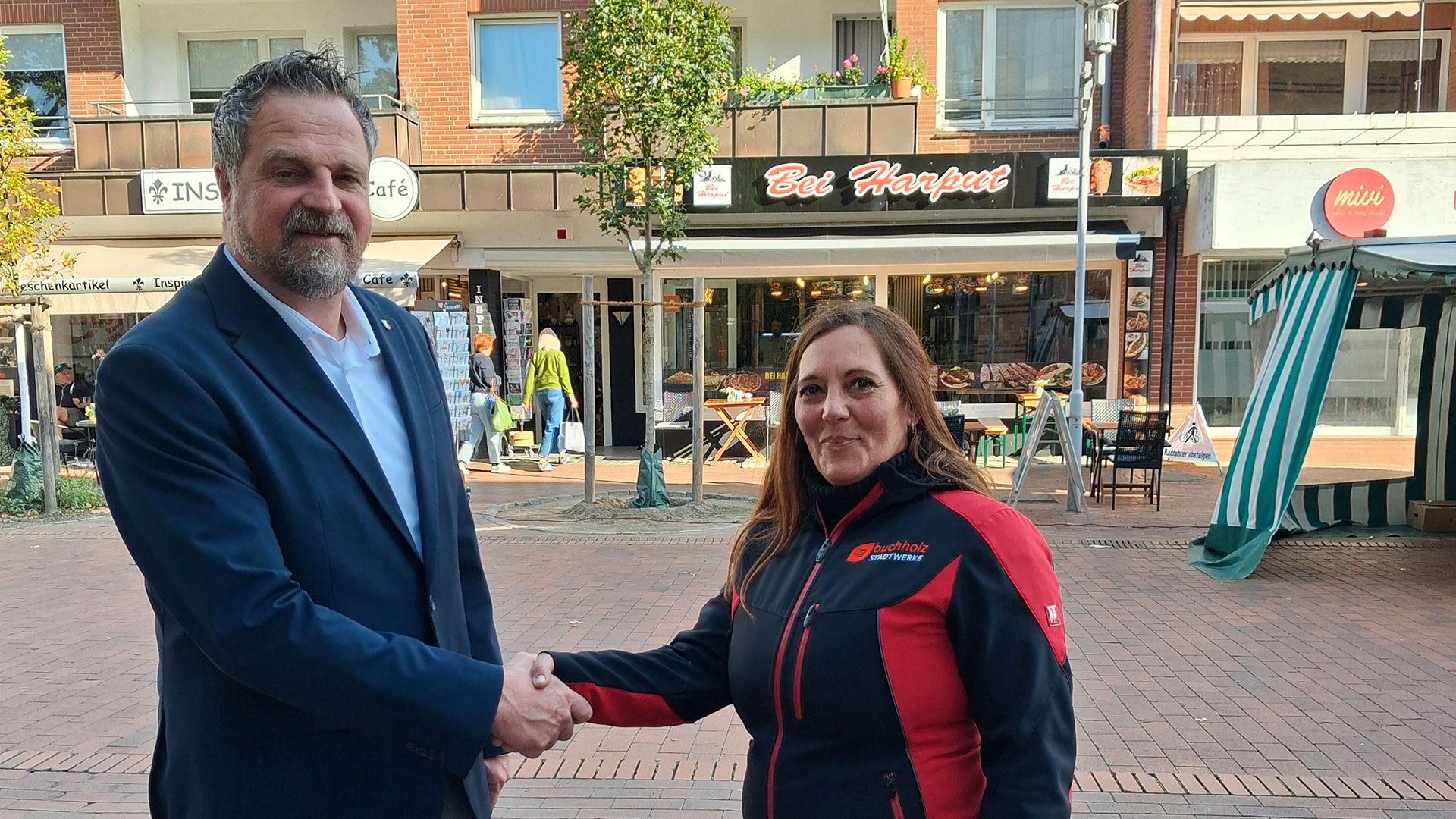 Michaela Voller (Stadtwerke Buchholz), Stadtbaurat Manuel Reichel und auf einem Foto Yasar Yildirim, der die Wasserpatenschaft übernommen hat. Foto: Stadt Buchholz