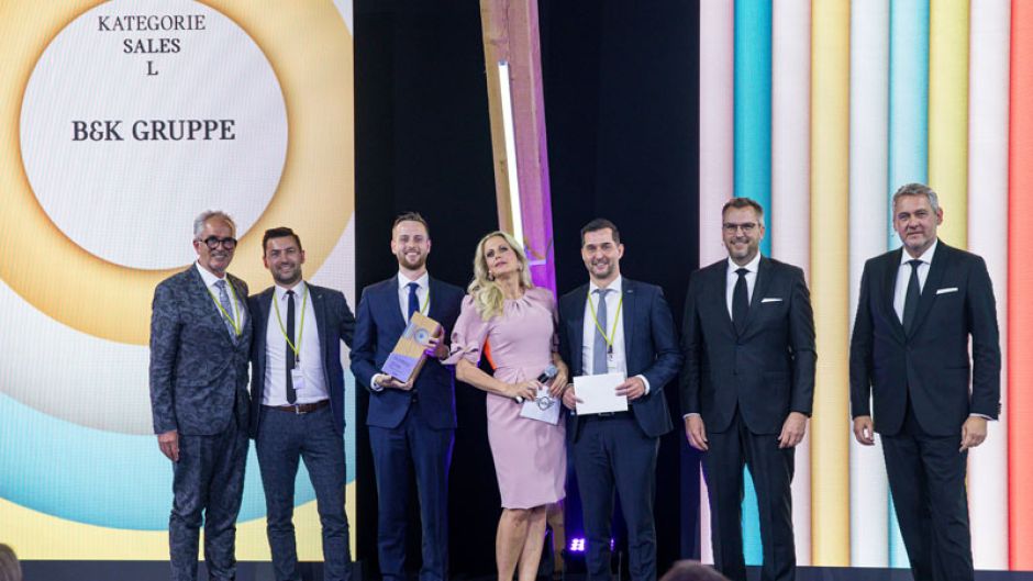 Burkard Weller von B&K freut sich über den 1. Platz bei den MINI Awards 2021 im Segment L. Überreicht wurde der Preis von Barbara Schöneberger. Von links: Burkhard Weller, Marcel Grätz, Julian Kaiser, Barbara Schöneberger, Torsten Döbbelin, Christan Brandl, Stefan Teuchert.