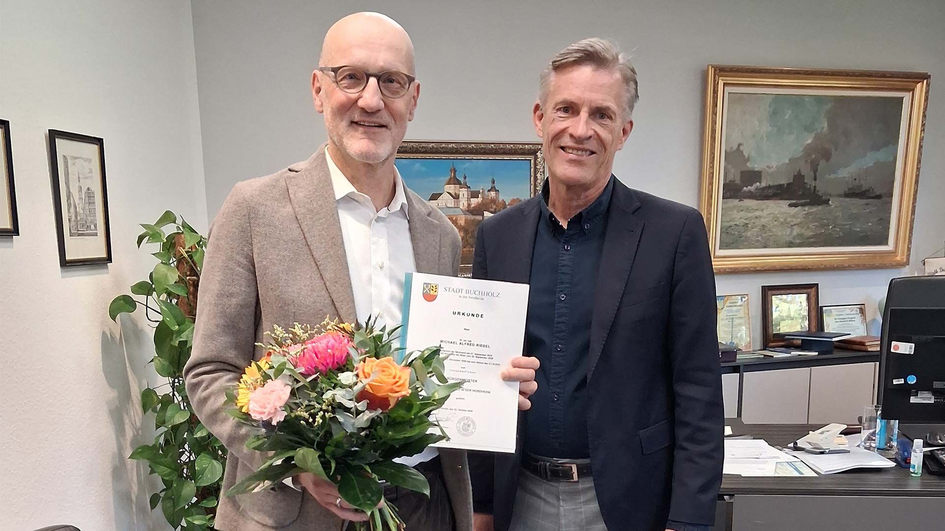Symbolische Urkundenübergabe von Bürgermeister Jan-Hendrik Röhse (rechts) an seinen Nachfolger Michael Riedel. Foto: Stadt Buchholz