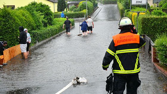 Das Unwetter sorgte im Bezirk für überflute Straßen und Keller. Anwohner wie hier im Falkenbergsweg in Neugraben versuchten, das Wasser mit Barrieren von ihren Häusern fernzuhalten oder es mit Besen auf die Straße zurück zu schieben.  | Foto: HamburgNews
