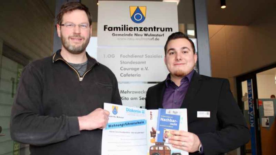 Johannes Mantzel (l, Diakonisches Werk der Kirchenkreise Hittfeld und Winsen) und Steffen Matthees, (r, Fachdienstleiter Soziales in der Gemeinde Neu Wulmstorf) vor dem Familienzentrum mit dem Plakat zum „Wohnungsführerschein“. | Foto: ein