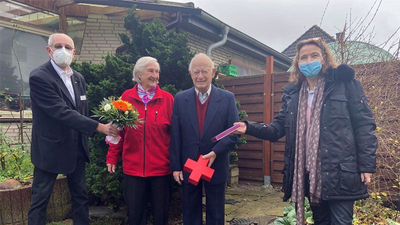 Mit Abstand und Maske: Karin Bischoff und Dr. Andreas B. Kummer überreichen dem Ehepaar Singer kleine Aufmerksamkeiten zu dem besonderen Anlass. | Foto: DRK Harburg