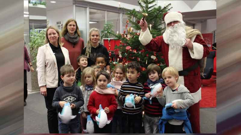 Gemeinsam mit dem Weihnachtsmann freuen sich die Kinder über ihren geschmückten Weihnachtsbaum im Sparkassen-Beratungscenter Harburg. | Foto; ein