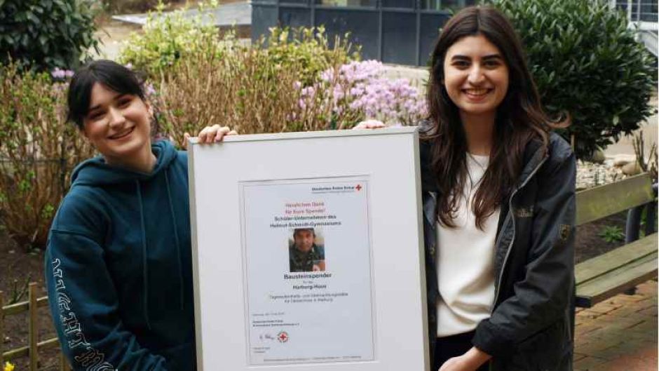 Hilal Caferoglu (rechts) und Ceyda Uzun von der Schülerfirma „SchmidtsKinners“ des Helmut Schmidt-Gymnasiums Wilhelmsburg mit der Urkunde für ihren Spenden-Baustein zugunsten der DRK-Obdachlosenherberge. | Foto: ein