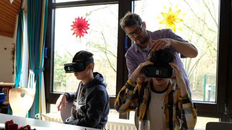 Jannek und Fabian lassen sich kurz beim Anlegen der VR-Brille helfen, und der virtuelle Besuch in Amsterdam kann beginnen. | Foto: ein