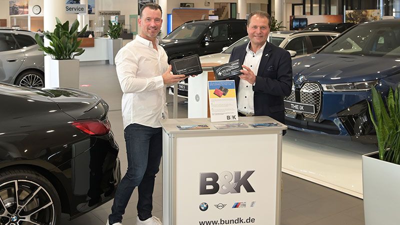 Filialleiter David Breuer (rechts) vom BMW Autohaus B&K übergibt dem langjährigen Kunden Andreas Kaiser von Kaiserwerbung den neuen Verbandskasten im Austausch für den alten und 15 Euro Spende.