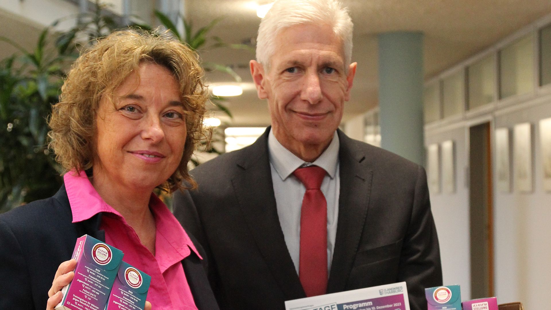 Wichtige Hilfe-Nummern finden sich auf den Taschentuchpackungen, die Gleichstellungsbeauftragte Andrea Schrag und Landrat Rainer Rempe verteilen. | Foto: Landkreis Harburg