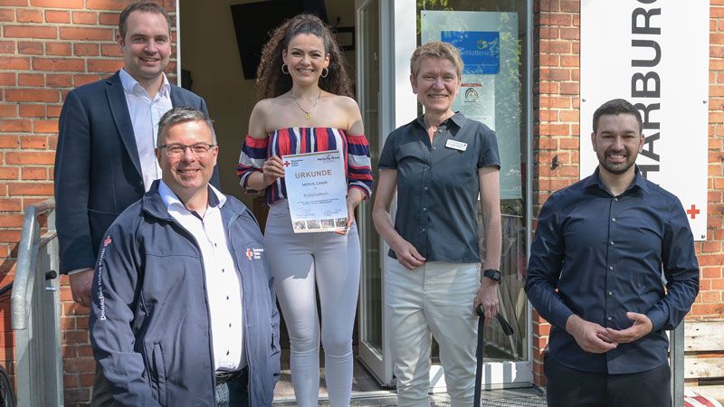 Merve Çakır (3.v.l.) erhielt von Harbrurg Huus-Leiter Thorben Goebel-Hansen (links), Dr. Simone Thiede (DRK, 4.v.l.) und Harald Halpik (Vorstand DRK Harburg, 2.v.l.)  die Urkunde als Botschafterin. Sami Musa (rechts) freute sich, dass der Kontakt, den er vermittelt hatte, so zu einem tollen Abschluss gekommen ist. | Foto: Niels Kreller