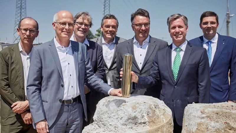 Die Zeitkapsel wird versenkt (im Bild (v.l.n.r.): Stefan Tebroke, Architekt von BHBVT, Dr. Peter Tschentscher, erster Bürgermeister der Hansestadt Hamburg, Prof. Dr. Hendrik Brinksma, Präsident der TUHH, Christian Langfeld, Leiter Abt. Bau der Fraunhofer-Gesellschaft, Prof. Dr.-Ing. Uwe Clausen, Leiter Fraunhofer IML, Prof. Dr.- Ing. Carlos Jahn, Leiter Fraunhofer CML, Dipl.-Päd. Ole John MBA, Baubeauftragter des CML. | Foto: CML