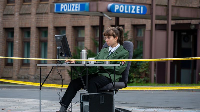Sinnbild für die Datenabfrage von persönlichen Daten kritischer Aktiver durch Polizisten: Eine Polizistin sitzt an einem PC. | Foto: JOTO