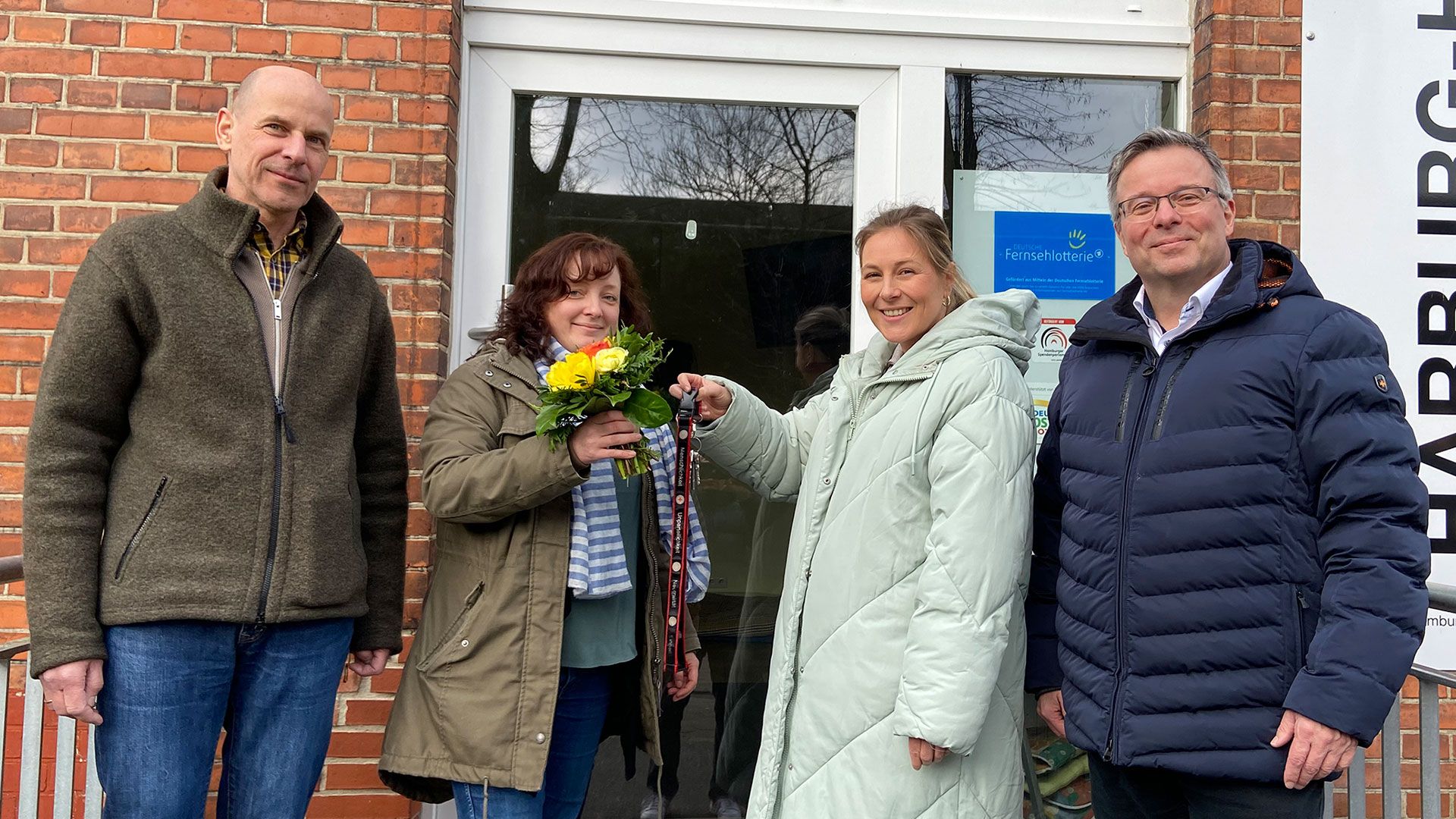 In Anwesenheit von Nicolai Panke (l.), DRK-Bereichsleiter Migration und Existenzsicherung und DRK-Harburg-Vorstand Harald Halpick (r.) überreicht Rosa Borgmann (2.vl.) der neuen Leiterin Dr. Janine Maimanakos den Schlüssel zum Harburg-Huus. | Foto. DRK Harburg