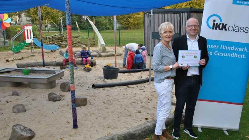 Sirke Reese-Krämer (von links) bedankt sich bei Stephan Jahn für die Auszeichnung. Im Hintergrund spielen Kinder unter dem Sonnensegel. | Foto: ein