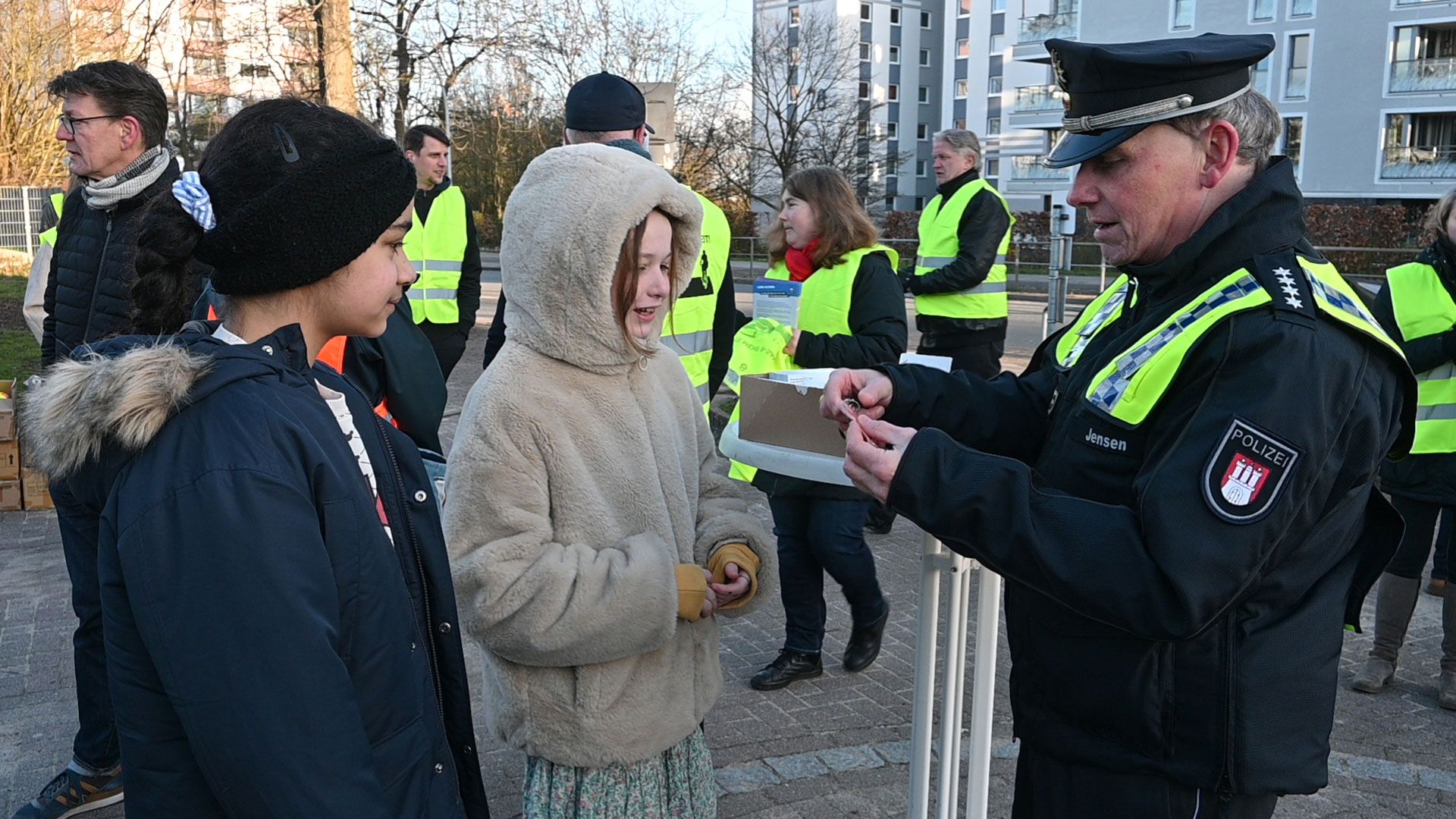Schulsprecherinnen Sabina (9 Jahre) und Clara (10 Jahre) bekommen von Michael Jensen (Stellv. Leiter VD 6) Reflektoren in Form von Ost-Ampelmännchen geschenkt. | Foto: Lenthe-Medien