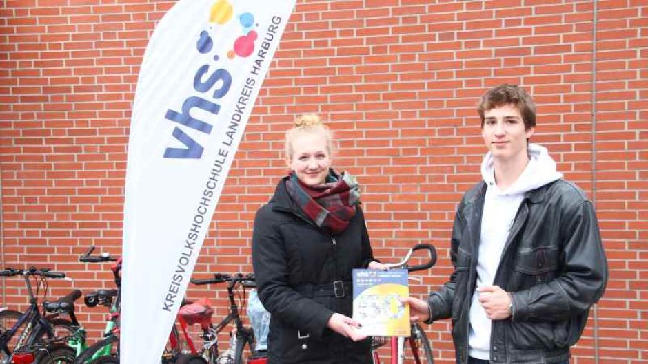 Franziska Wille, KVHS-Mitarbeiterin im Bereich Sprachen und Integration, überreicht ein Programmheft an Elrik Vosberg. | Foto: ein