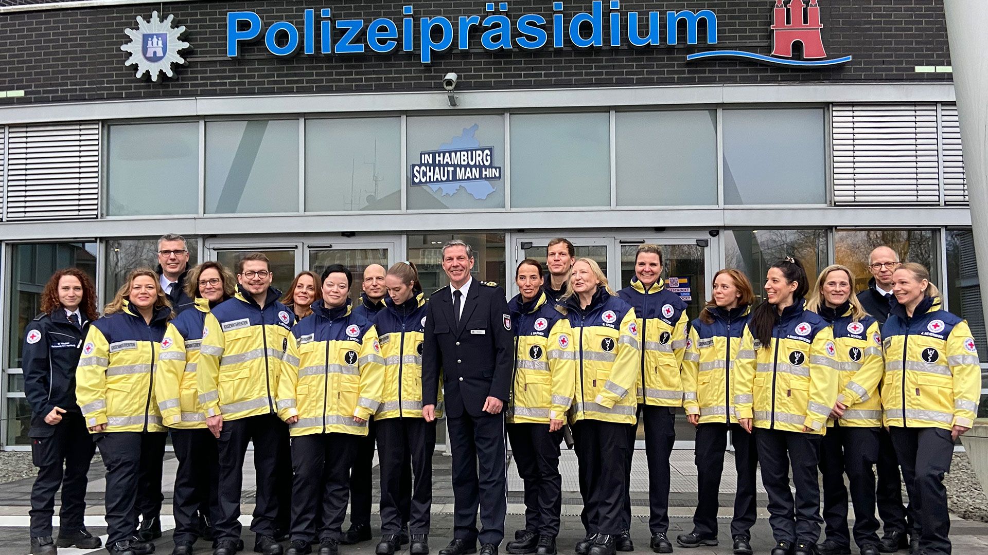 Polizeivizepräsident Mirko Streiber (Mitte) mit den neuen Mitgliedern und Ausbildern des Hamburger DRK-Kriseninterventionsteams auf den Treppen des Polizeipräsidiums. | DRK Hamburg-Harburg 2025